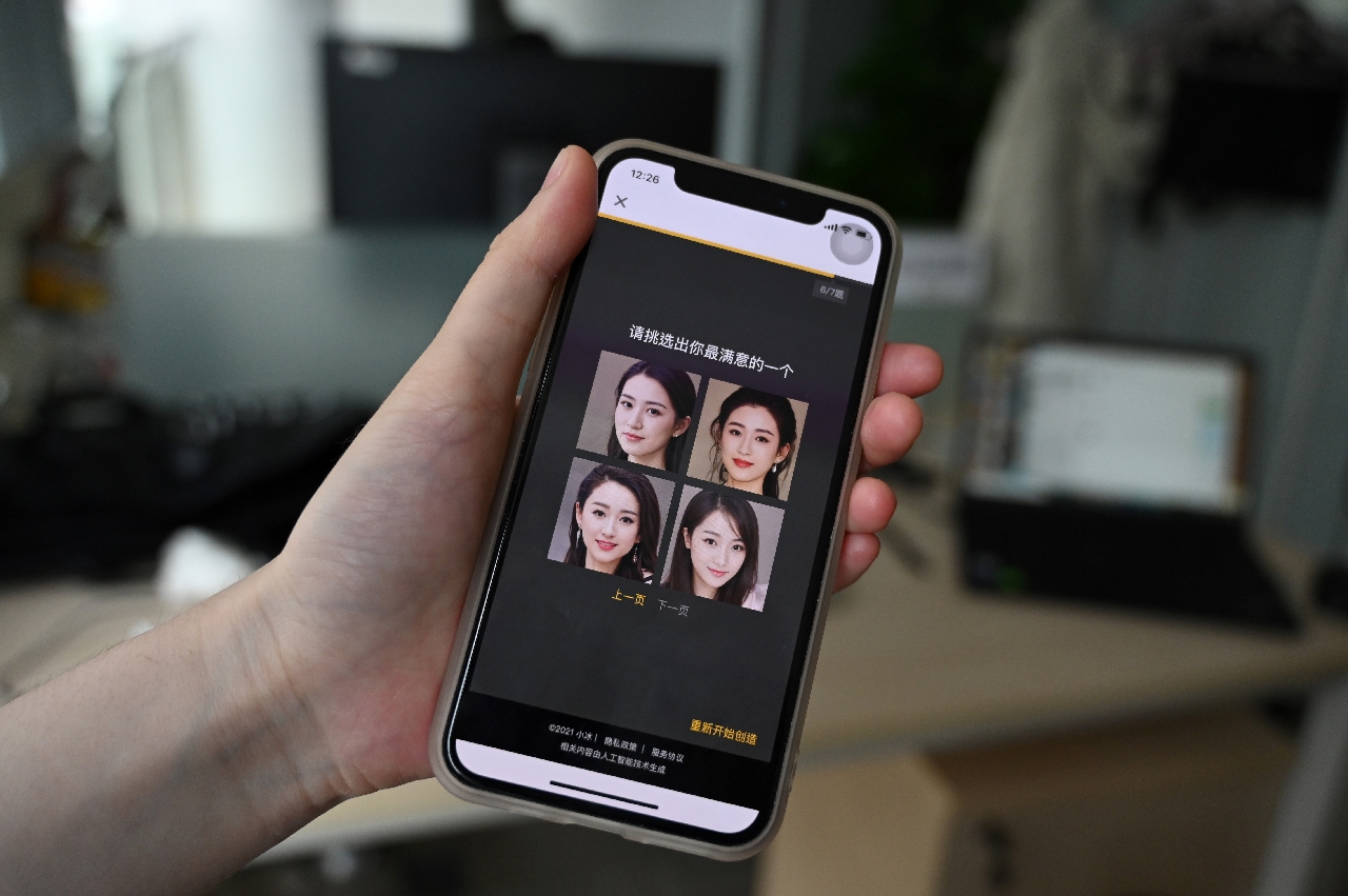 An employee of XiaoIce displays pictures of virtual women who can be chosen as friends on their smartphone on July 5, 2021 in Beijing.
