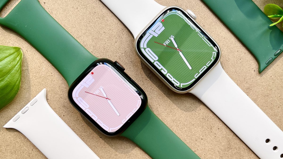 Two green Apple Watch Series 7s sit on a desktop, side by side.